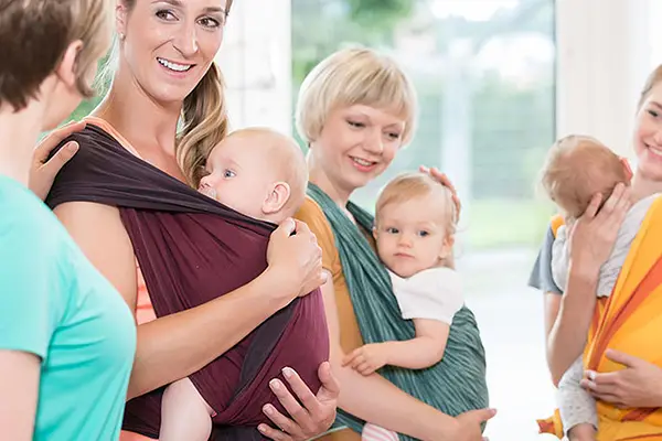 Mütter machen Kanga-Training mit ihren Babys in der Trage, stärkt ihre Fitness und genießt die Nähe zum Kind.